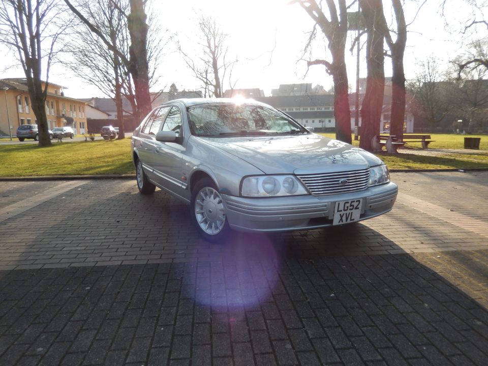 Silver 1999 Ford Fairlane sedan, front quarter view, parked on brick driveway.