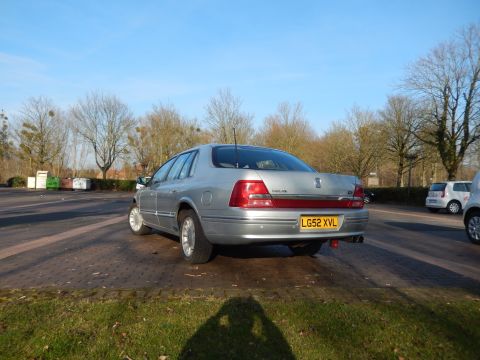 1999 Ford Fairlane - The rear passenger side of a silver sedan is parked on a paved lot with trees in the background. The license plate reads "LG52 XVL".