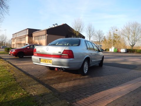 1999 Ford Fairlane - A silver Ford sedan is parked on a brick surface in front of a building. The car has a red stripe across the rear and a yellow license plat…