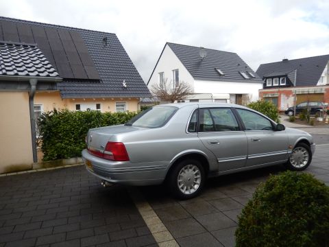 1999 Ford Fairlane - A silver sedan is parked in front of houses with solar panels on the roof.