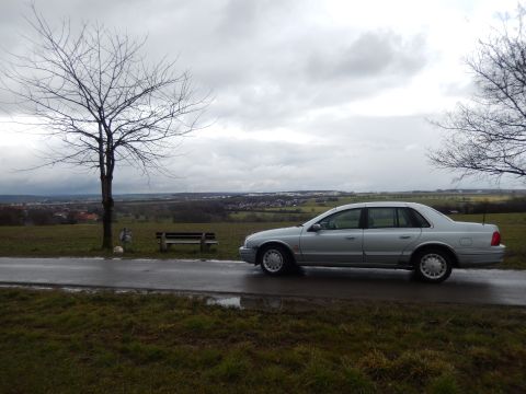1999 Ford Fairlane - Silver 1999 Ford Fairlane sedan parked on a wet road under an overcast sky.
