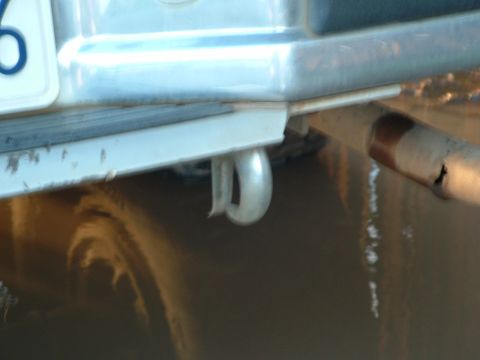 1990 Ford Bronco - A close-up view of a vehicle's rear bumper, tow hook, and exhaust pipe.