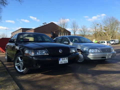 1999 Ford Fairlane - Two full-size sedans, a black Mercury Grand Marquis and a silver Ford LTD Crown Victoria, are parked side-by-side on a sunny day.