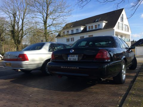 1999 Ford Fairlane - A black Mercury Marauder is parked next to a silver sedan on a sunny day.