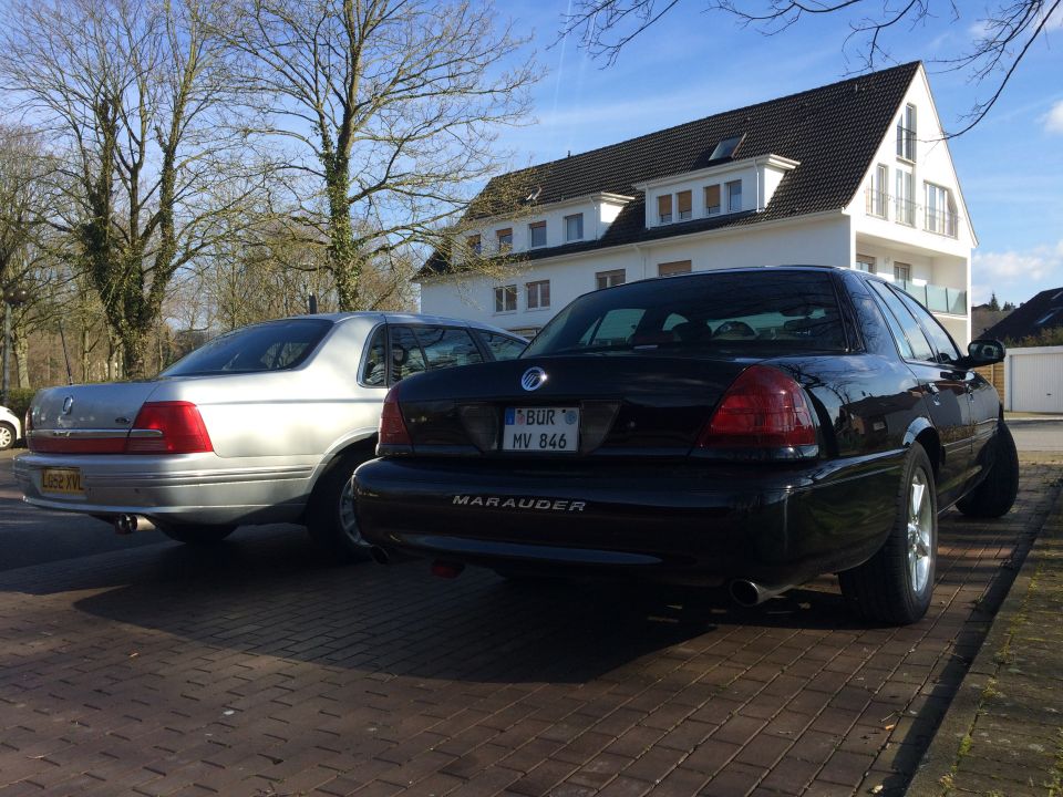 Black Mercury Marauder and silver sedan parked on brick driveway