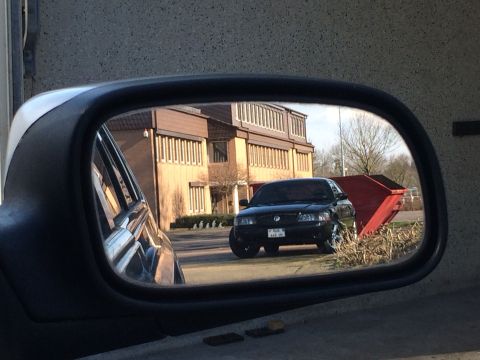 1999 Ford Fairlane - A black sedan, likely a Mercury Grand Marquis, is seen in the side mirror of another vehicle.