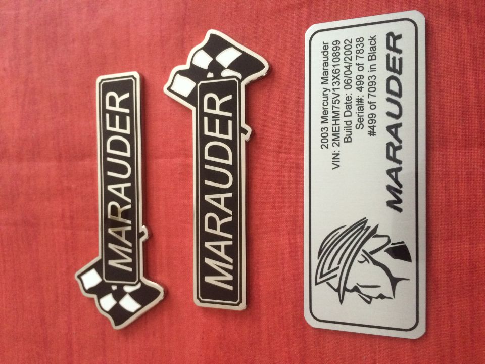 Two Marauder emblems and a VIN plate for a 2003 Mercury Marauder