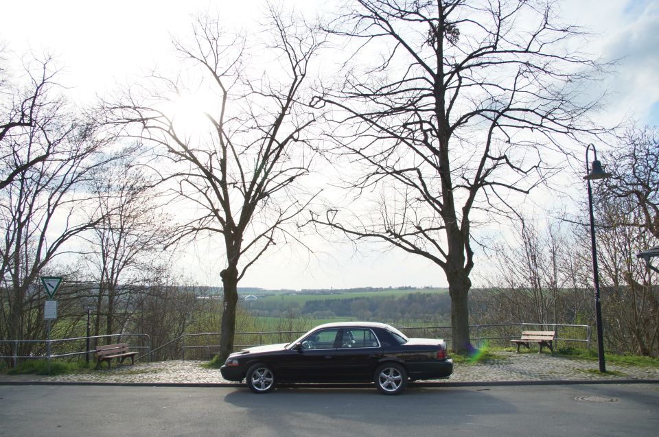 2003 Mercury Marauder parked on the side of a road with trees and a field in the background