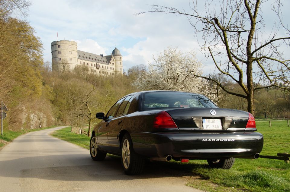 2003 Mercury Marauder parked on a road, rear view, with a castle on a hill behind it