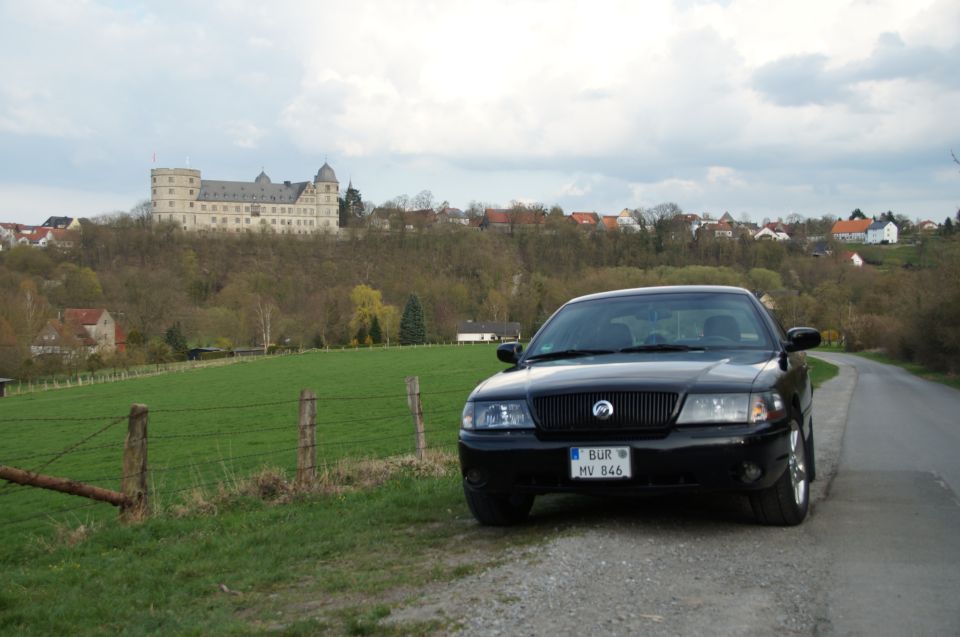 2003 Mercury Marauder parked on a dirt road, front view. Castle and village in background