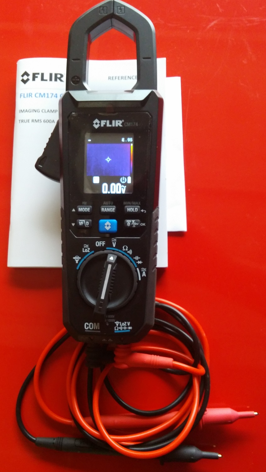 FLIR CM174 imaging clamp meter with leads and manual on red surface