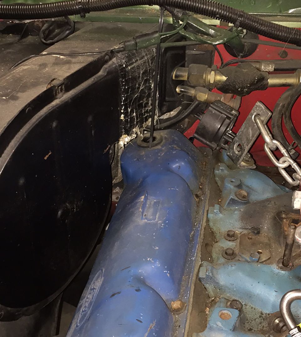 Engine bay with blue valve covers and black fender liner. Wires and hoses are visible