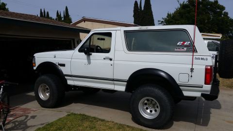 1992 Ford Bronco - This lifted 1992 Ford Bronco is parked in a suburban driveway with a garage in the background.