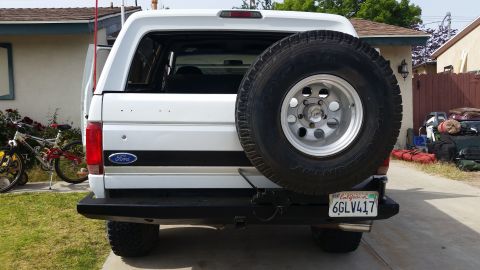 1992 Ford Bronco - Rear view of a white 1992 Ford Bronco, showing its spare tire and California license plate.