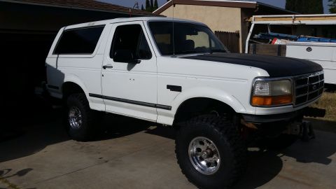 1992 Ford Bronco - This lifted 1992 Ford Bronco is parked in front of a garage with a utility truck in the background.