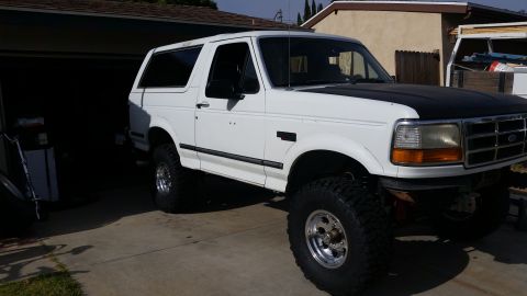 1992 Ford Bronco - This 1992 Ford Bronco is shown from a three-quarter front angle, lifted with off-road tires and a contrasting black hood.