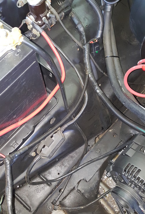 Engine bay with battery, alternator, and wiring harness visible