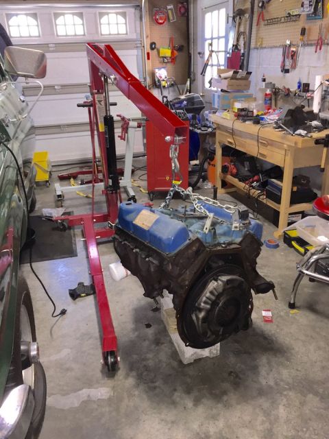 1978 Ford Bronco - An engine hoist is used to lift a V8 engine out of a vehicle in a garage.