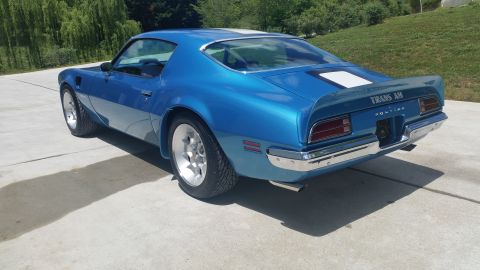 1970 Pontiac Trans Am - A blue 1970 Pontiac Trans Am is parked on a concrete surface with a white stripe on its rear deck and spoiler.