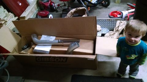 1994 Ford Bronco - A Gibson exhaust pipe is shown inside its shipping box, with a young child standing nearby.