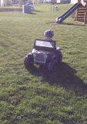 1994 Ford Bronco - A child sits in a toy Jeep parked on a lawn with a slide in the background.