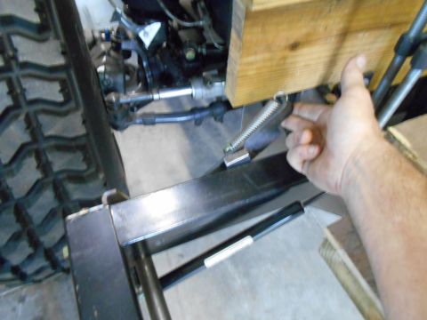 1992 Ford Bronco - A close-up view of a vehicle's steering and suspension system, with a hand interacting with a spring mechanism.