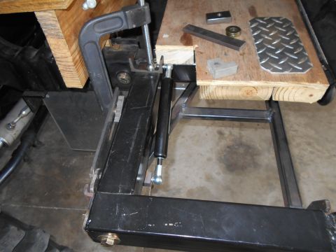 1992 Ford Bronco - Various metal parts and a diamond plate are laid out on a wooden surface, secured by a clamp.