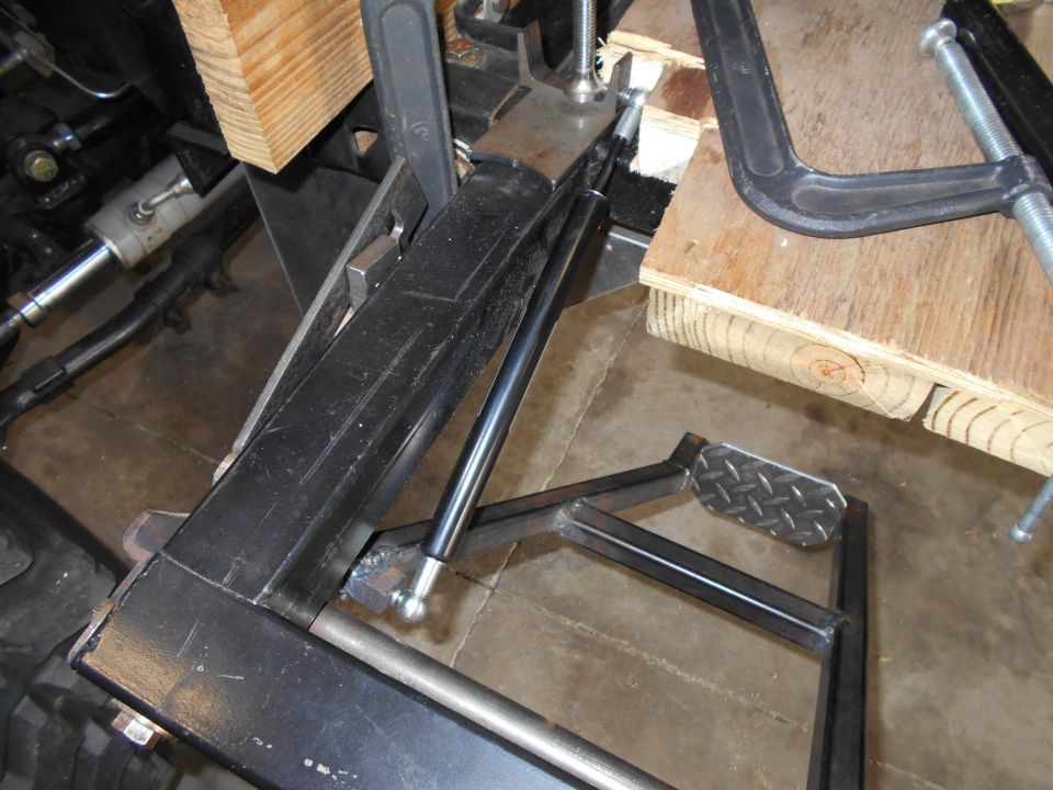 Close-up of vehicle frame or suspension part held by clamps and wood blocks
