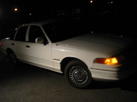 1994 Ford Crown Victoria - A white sedan is parked at night, showing its front quarter panel and side profile.