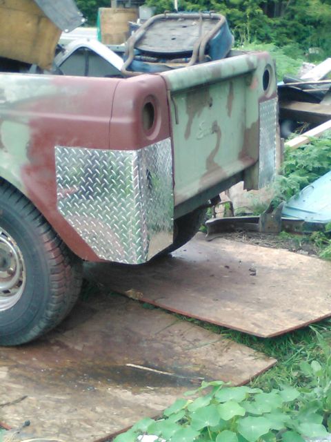 1991 Ford Bronco - The rear corner of a vintage pickup truck bed is shown, featuring diamond plate aluminum protection on the fender and bedside. The truck be…