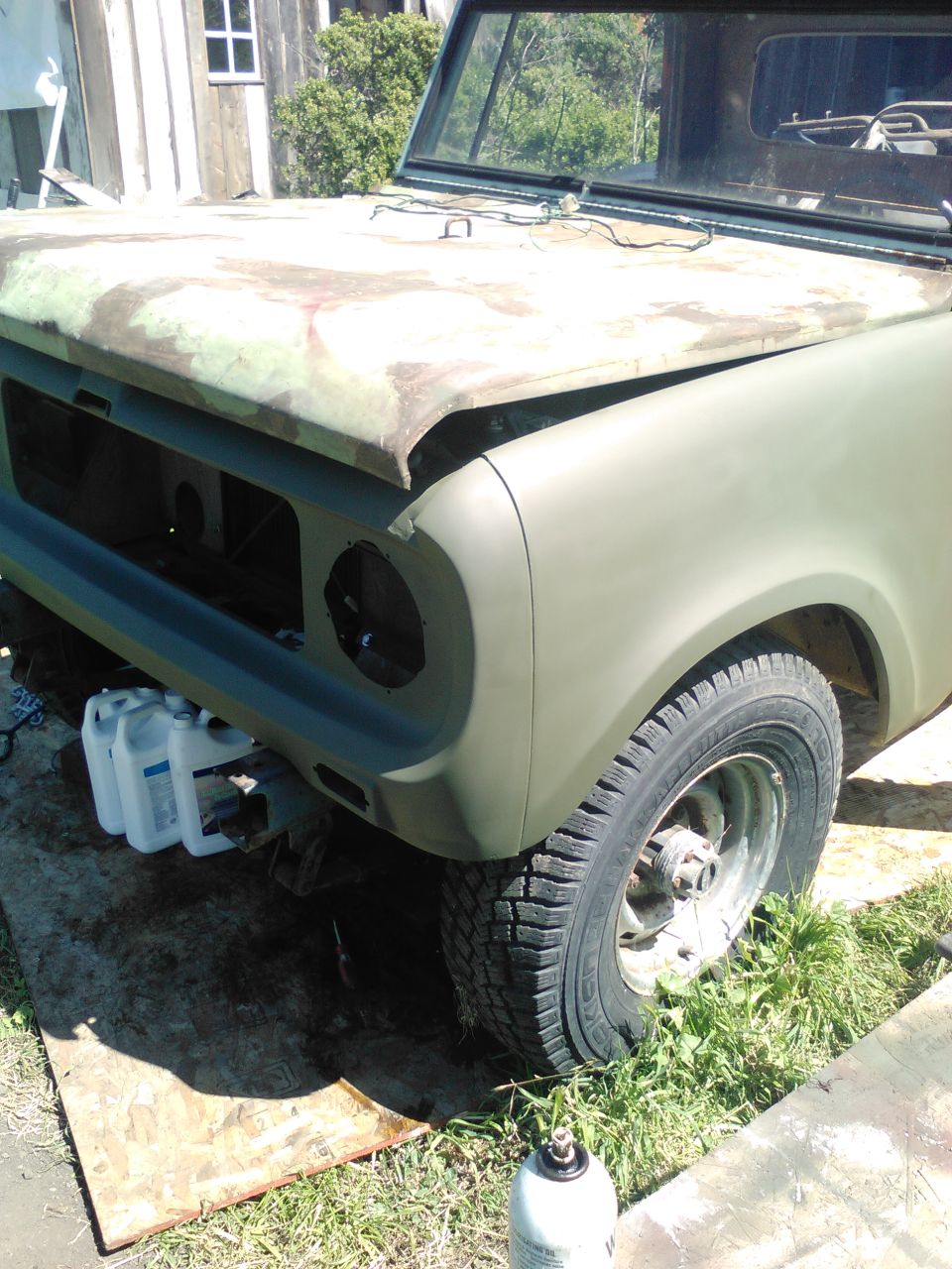 Front fender and hood of an olive drab vintage utility vehicle, possibly undergoing restoration.