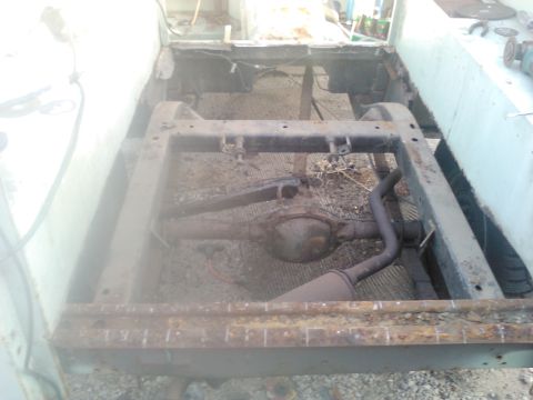 1991 Ford Bronco - The underside of a vehicle frame is shown, with the rear axle, exhaust system, and leaf springs visible. The frame appears to be undergoing…