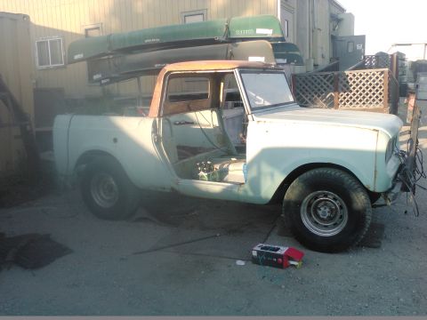1991 Ford Bronco - A light blue pickup truck with the doors and hood removed is parked outdoors. Several canoes are stacked on top of the truck's bed and cab.