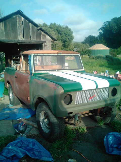 1991 Ford Bronco - A vintage pickup truck, possibly an International Harvester Scout, is parked in front of a wooden barn. The truck is partially painted gree…