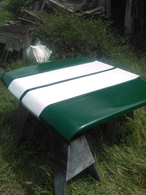 1991 Ford Bronco - A green car hood with white racing stripes is resting on sawhorses outdoors. The hood is curved and appears to be freshly painted.