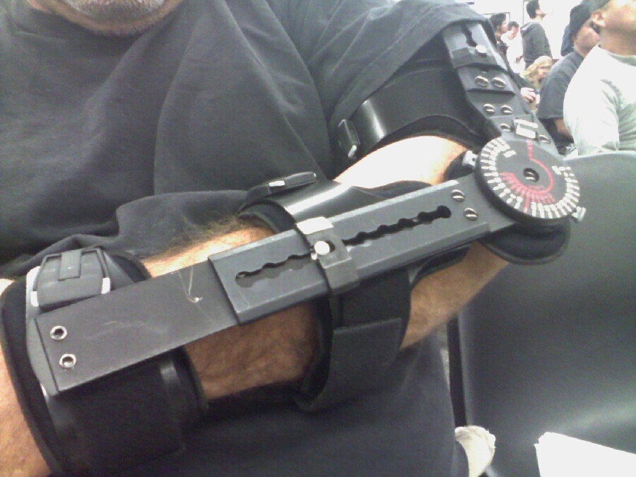 Close-up of a black adjustable brace on a person's arm with a circular dial.