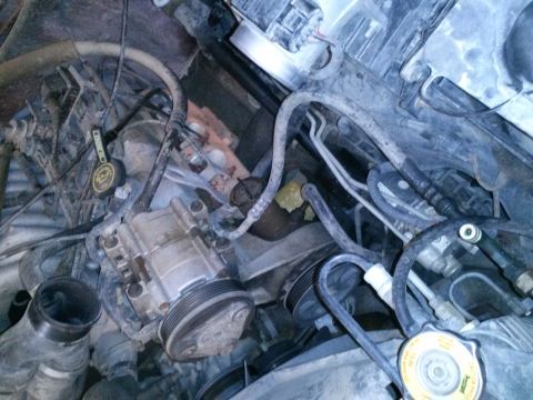 1996 Ford Bronco - This is a close-up, overhead view of a vehicle's engine bay, focusing on the air conditioning compressor and various hoses and belts. The e…