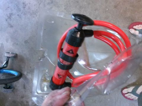 1996 Ford Bronco - A hand is holding a red and black bicycle pump with a coiled red hose. The pump is inside a clear plastic package on a concrete floor. A bi…