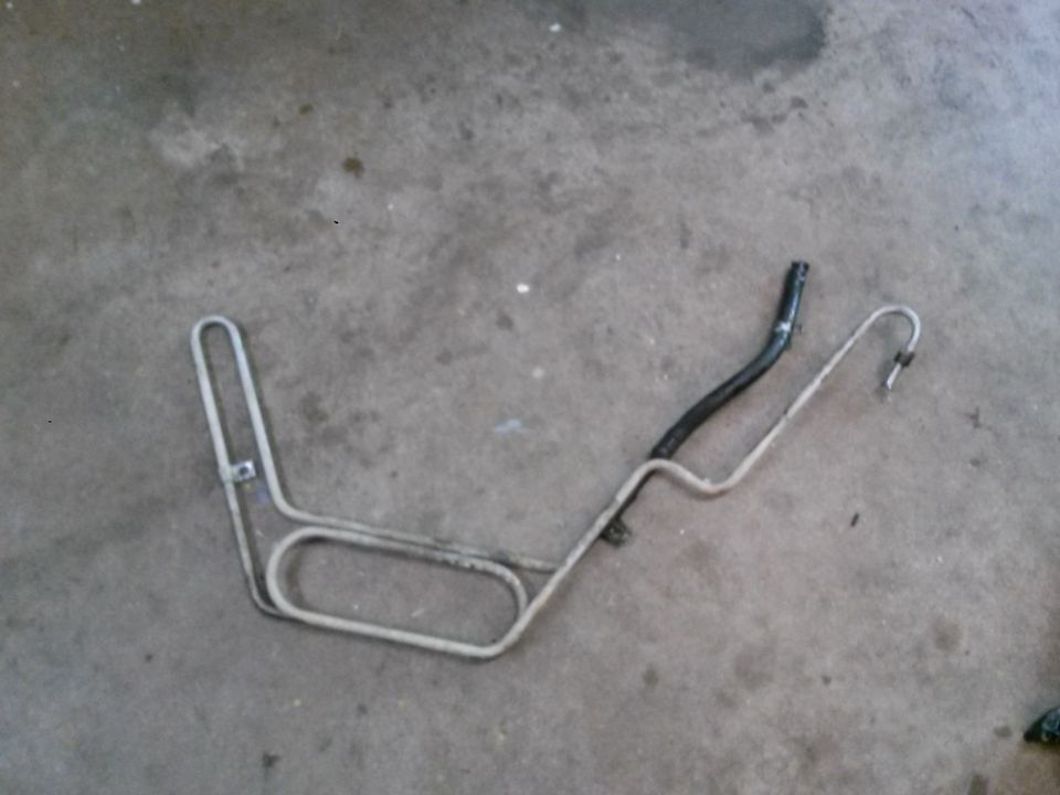 Bent metal tube with black hose on concrete