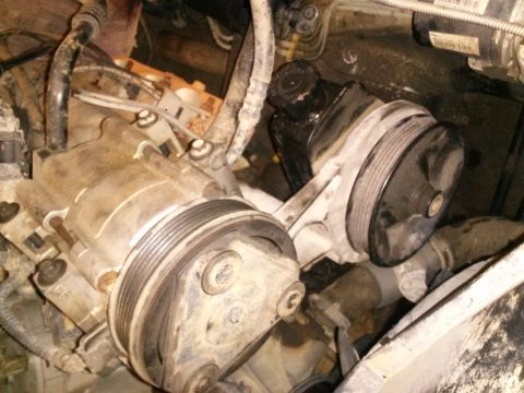 1996 Ford Bronco - This image shows a close-up view of the engine bay of a 1996 Ford Bronco, focusing on the power steering pump and the air conditioning comp…
