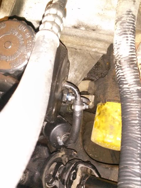 1996 Ford Bronco - A close-up view of a vehicle's engine bay shows a black inline fuel filter with a rubber hose attached and secured by hose clamps. A yellow…