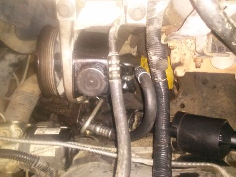 1996 Ford Bronco - A close-up view of the power steering pump and pulley system in a vehicle engine bay. The black power steering pump is visible with hoses c…