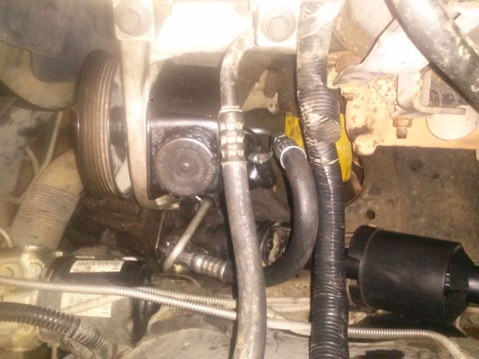 Power steering pump and pulley in vehicle engine bay.