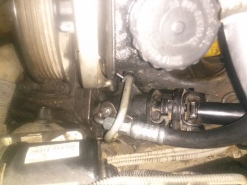 1996 Ford Bronco - This is a close-up view of a vehicle's engine bay, focusing on the power steering pump and steering column components. A metal pulley and v…