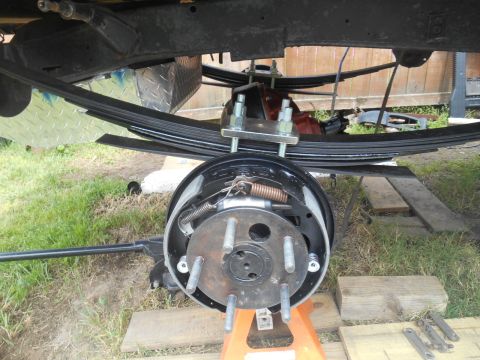 1972 Ford Bronco - A close-up view of the rear suspension and brake assembly of a vehicle, likely a 1972 Ford Bronco, showing leaf springs, a brake drum, and…