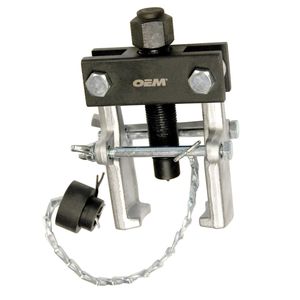 1996 Ford Bronco - A close-up, slightly angled view of a silver and black gear puller tool with a black rubber adapter attached by a metal chain. The tool has…