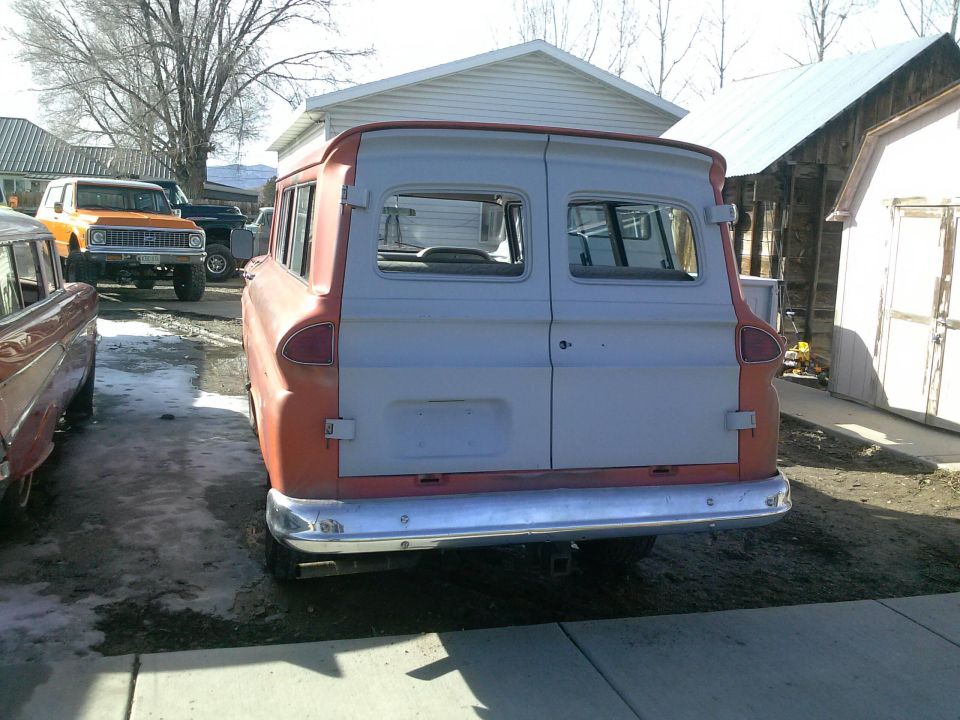Rear view of a vintage orange and gray panel van with chrome bumper.