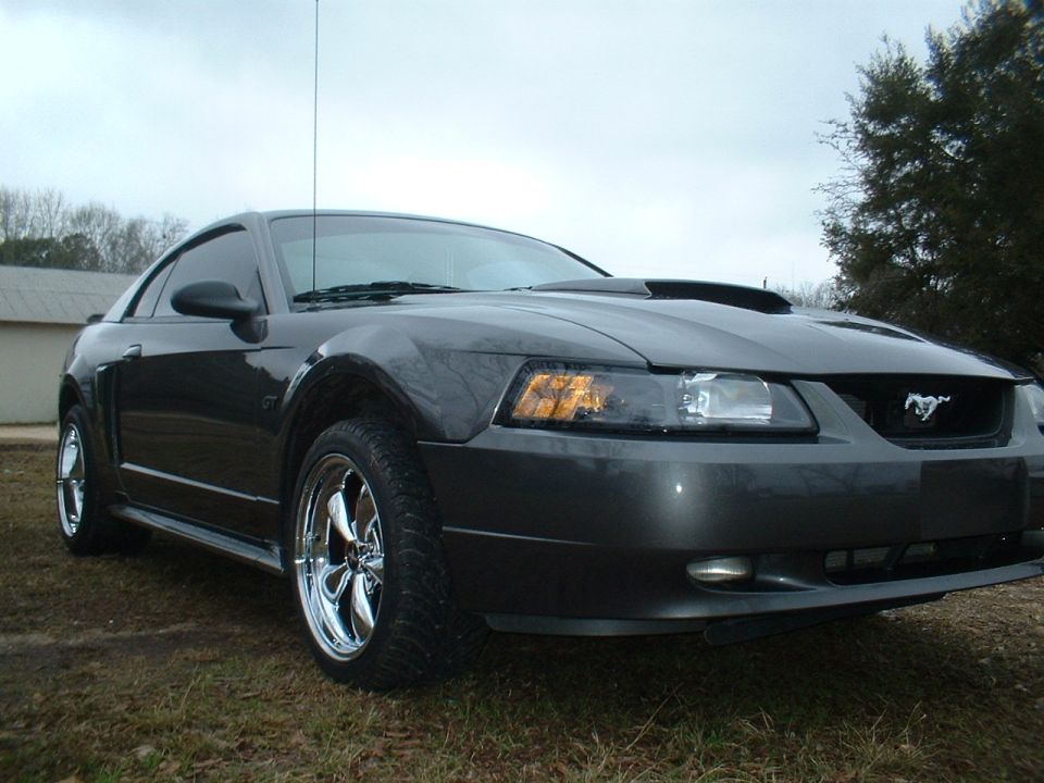 Dark gray 2003 Ford Mustang coupe with chrome wheels, hood scoop, and a horse emblem on the grille