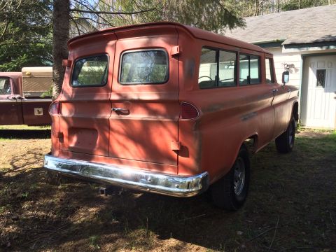 1962 Chevrolet Suburban - The rear passenger side of a faded orange 1962 Chevrolet Suburban, nicknamed "Chester", is shown parked outdoors next to a white building.…