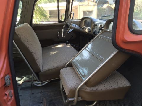 1962 Chevrolet Suburban - The interior of a vintage Chevrolet Suburban shows the front seats and dashboard. The driver's seat is upholstered in a patterned fabric wi…